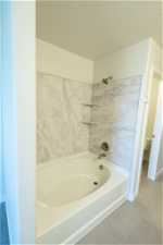 Bathroom featuring shower / bath combination, toilet, a textured ceiling, and tile flooring