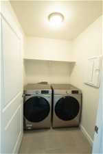 Clothes washing area featuring washer and dryer, light tile floors, and washer hookup