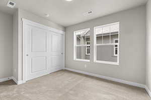 Unfurnished bedroom with light colored carpet and a closet