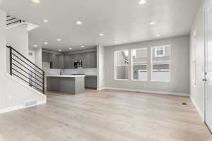 Unfurnished living room with sink and light wood-type flooring