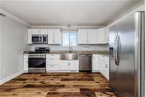Kitchen featuring white cabinets, dark hardwood / wood-style flooring, and appliances with stainless steel finishes