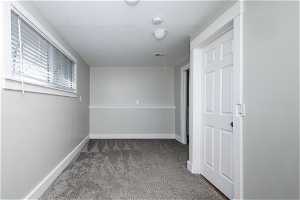 Hallway featuring a textured ceiling and carpet flooring