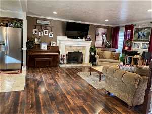 Living room featuring crown molding, dark tile flooring, a brick fireplace, and a textured ceiling