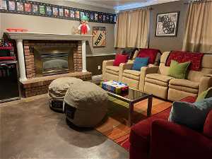 Living room featuring concrete flooring, a brick fireplace, and crown molding