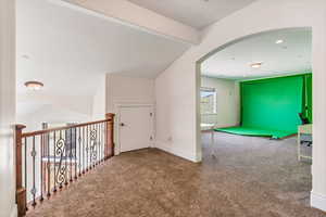 Corridor with lofted ceiling with beams and carpet