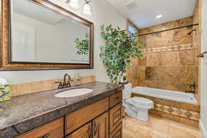 Full bathroom with tiled shower / bath combo, vanity, toilet, and tile flooring