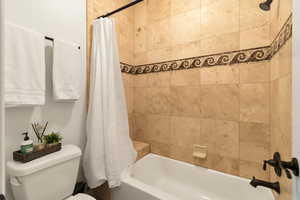 Bathroom with toilet and shower / bath combo with shower curtain