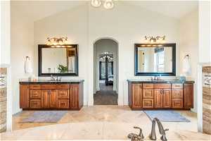 Bathroom featuring high vaulted ceiling, dual bowl vanity, and tile flooring