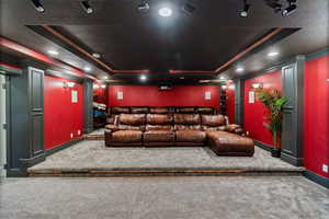 Carpeted cinema room featuring a raised ceiling