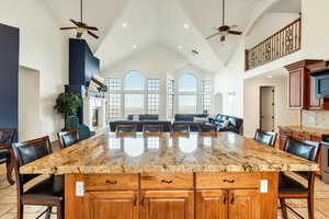 Kitchen with a kitchen bar, ceiling fan, tasteful backsplash, and high vaulted ceiling