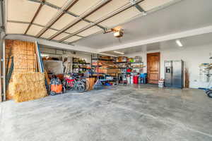 Garage featuring stainless steel fridge with ice dispenser, strapped water heater, and a garage door opener