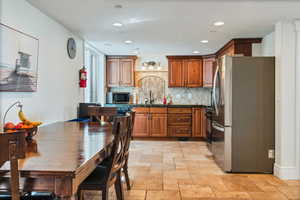 Kitchen with appliances with stainless steel finishes, sink, tasteful backsplash, and light tile flooring