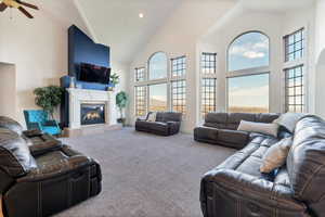 Carpeted living room featuring ceiling fan and high vaulted ceiling