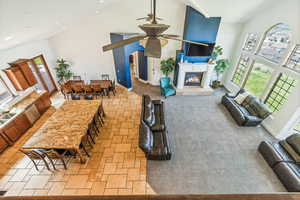 Living room with high vaulted ceiling, tile flooring, ceiling fan, and a fireplace