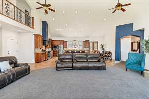 Carpeted living room featuring ceiling fan and high vaulted ceiling