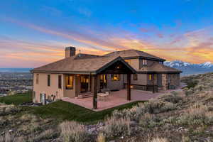 Back house at dusk featuring a patio area, a mountain view, and central AC unit