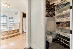 Walk in closet with a chandelier and light tile flooring