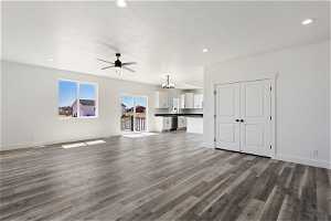 Unfurnished living room with ceiling fan with notable chandelier and hardwood / wood-style flooring