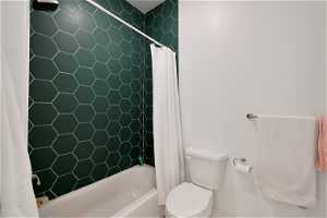 Bathroom with toilet and shower / bath combo with shower curtain