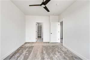 Unfurnished bedroom featuring a closet, ceiling fan, a walk in closet, and light carpet