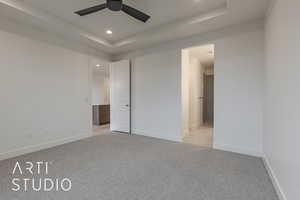 Unfurnished bedroom with a raised ceiling, ensuite bath, ceiling fan, and light carpet