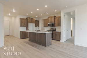 Kitchen with light hardwood / wood-style floors, sink, an island with sink, and appliances with stainless steel finishes