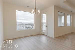 Interior space featuring plenty of natural light, an inviting chandelier, and light hardwood / wood-style flooring