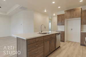 Kitchen with sink, an island with sink, stainless steel dishwasher, and light hardwood / wood-style flooring