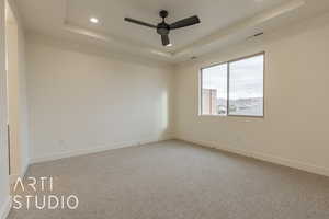 Unfurnished room with carpet flooring, ceiling fan, and a raised ceiling