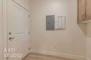 Washroom featuring electric panel, cabinets, and light wood-type flooring