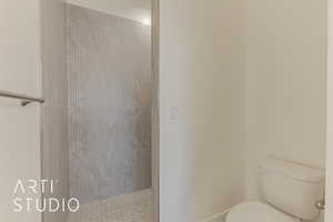 Bathroom featuring tiled shower and toilet