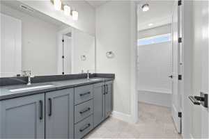 Bathroom featuring tile floors, dual vanity, and bathing tub / shower combination