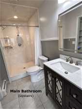 Bathroom with walk in shower, vanity, toilet, and tile flooring