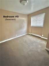 Carpeted spare room featuring baseboard heating