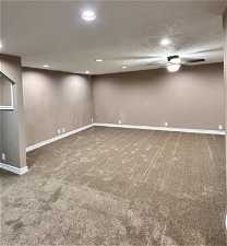 Basement featuring a textured ceiling, ceiling fan, and carpet flooring