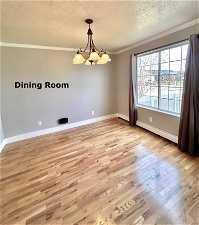Unfurnished room featuring crown molding, a chandelier, light wood-type flooring, and a baseboard radiator