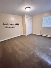 Spare room featuring dark carpet and a baseboard radiator