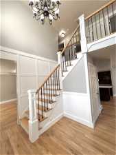 Stairs featuring a chandelier and light hardwood / wood-style flooring