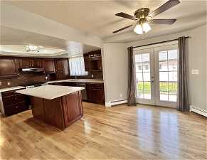 Kitchen with french doors, backsplash, light hardwood / wood-style flooring, a baseboard radiator, and range hood