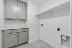 Washroom with cabinets, hookup for an electric dryer, light tile floors, and washer hookup
