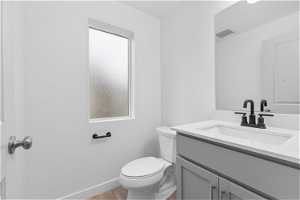 Bathroom with vanity with extensive cabinet space, hardwood / wood-style flooring, and toilet