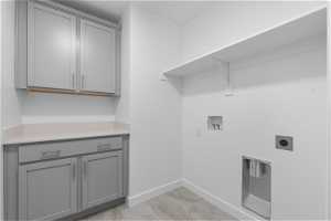 Clothes washing area with cabinets, hookup for an electric dryer, and washer hookup