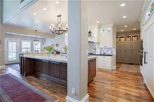 Kitchen featuring hardwood / wood-style flooring, a large island with sink, hanging light fixtures, and backsplash