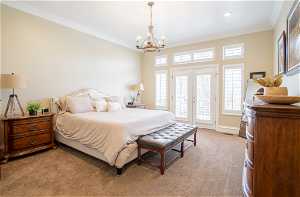 Carpeted bedroom with multiple windows, crown molding, and access to outside
