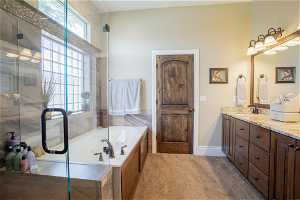 Bathroom with double vanity, a wealth of natural light, and plus walk in shower
