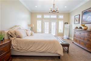 Bedroom with an inviting chandelier, carpet, access to outside, and crown molding