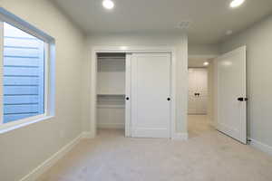 Unfurnished bedroom with light carpet and a closet