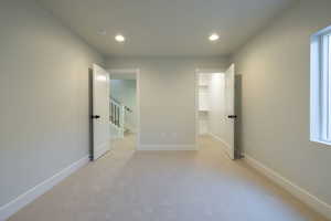 Unfurnished bedroom with a walk in closet and light carpet