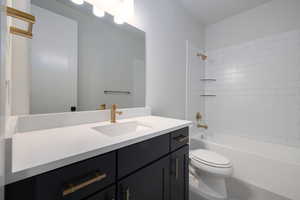 Full bathroom with tiled shower / bath combo, vanity with extensive cabinet space, toilet, and tile floors