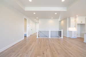 Unfurnished room with a tray ceiling and light wood-type flooring